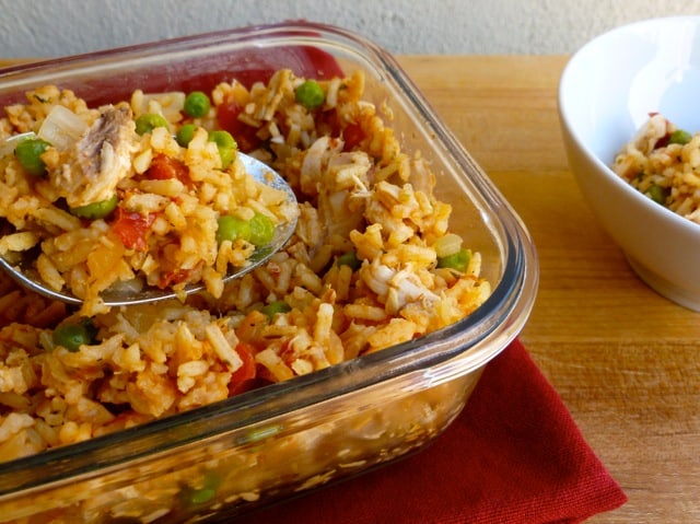 Easy arroz con pollo in glass serving dish with spoon.