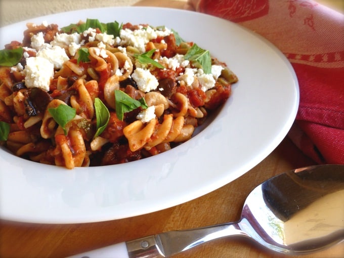 Pasta with tomatoes, chicken and garnished with feta cheese and fresh basil.