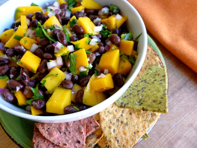 Black Bean Mango Salsa in white bowl with baked tortilla chips.