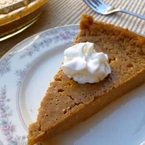 bisquick impossible pumpkin pie with a dollpp of whipped topping on china plate