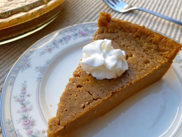 bisquick impossible pumpkin pie with a dollpp of whipped topping on china plate