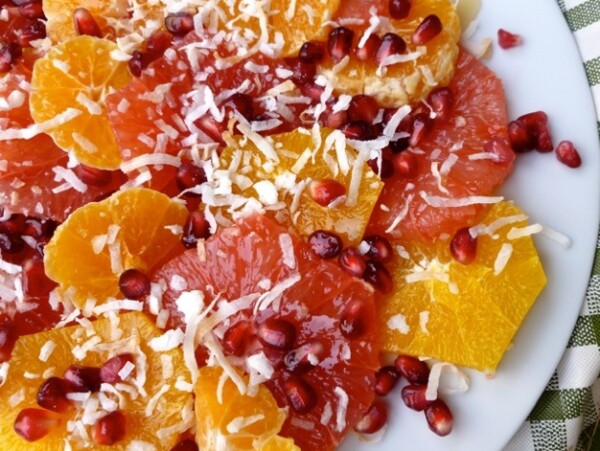 sliced oranges, pink grapefruit slices with coconut and pomegranate arils from above white plate