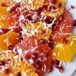 sliced oranges, pink grapefruit slices with coconut and pomegranate arils from above white plate