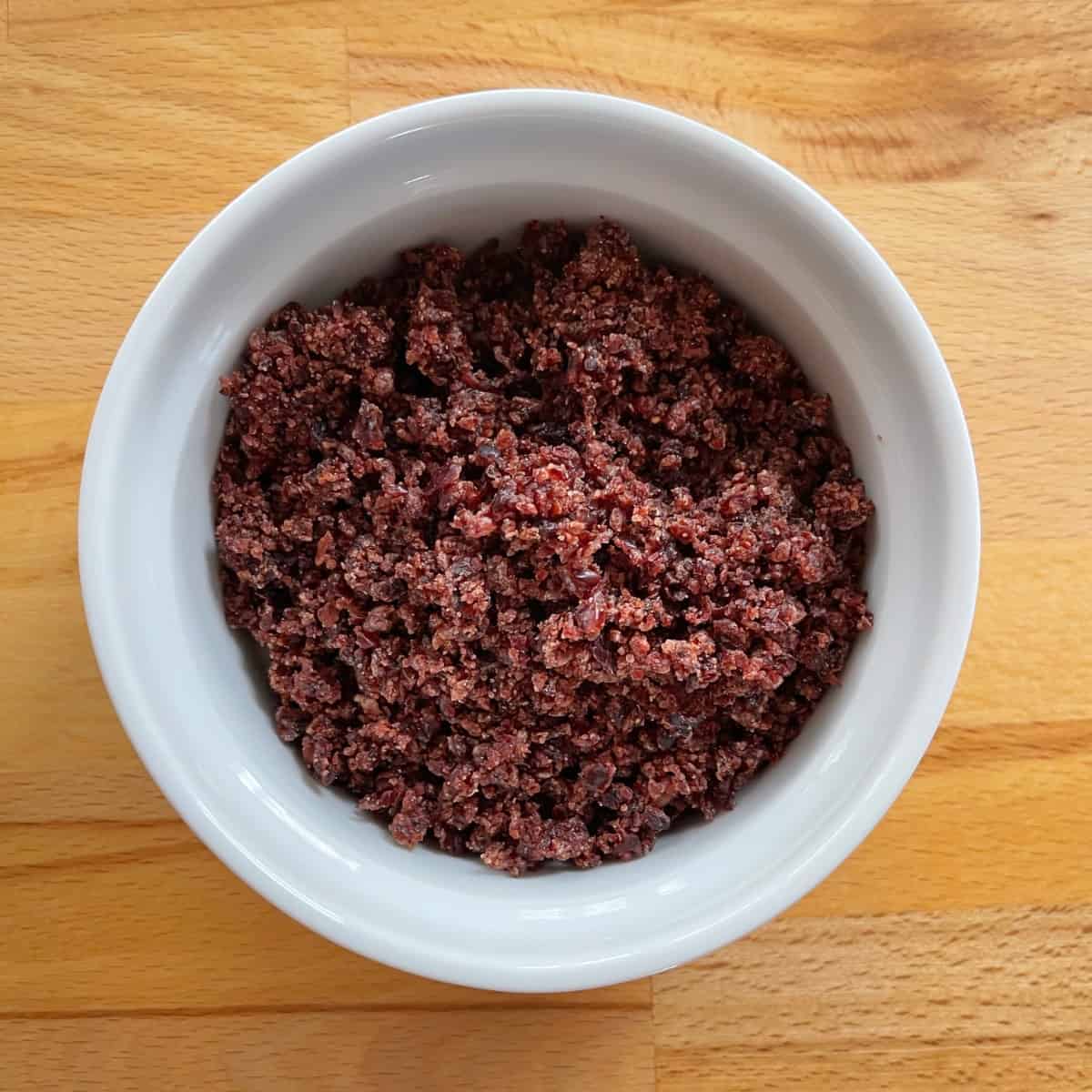 Finely chopped dried cranberries in white ramekin from above.