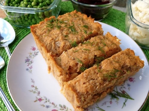 Weight Watchers Salmon Dill Loaf sliced on serving plate with peas and mashed potatoes in background.