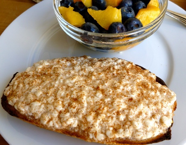 Cottage Cheese on Toast with cinnamon alongside bowl of blueberries and peaches.