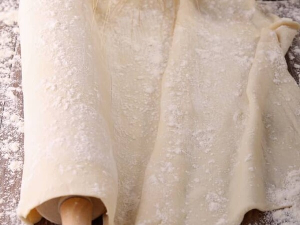 Flatbread dough with a rolling pin and bowl of flour