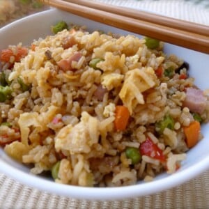 white bowl with ham veggie fried rice with chopsticks along rim