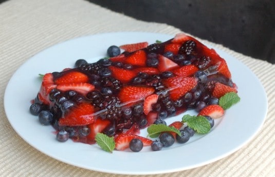 Mixed Berry Summer Fruit Terrine with strawberries, blueberries and blackberries on serving plate with fresh mint.