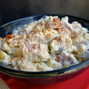 Creamy Red, White and Blue Potato Salad in blue bowl on red mat