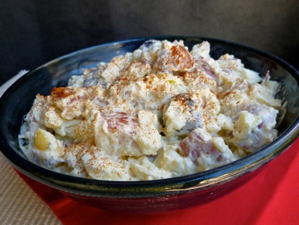 Creamy Red, White and Blue Potato Salad in blue bowl on red mat