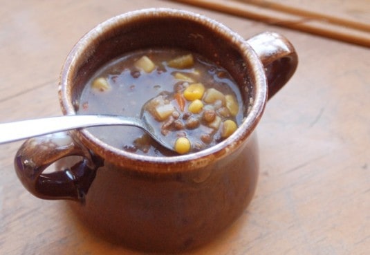 Leftover Beef Vegetable Lentil Soup in brown soup crock with spoon.