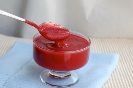 Simple raspberry sauce in glass dish with spoon.