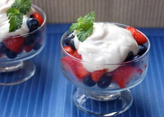 Fresh strawberries and blueberries in a glass dish with yogurt and sprig of mint
