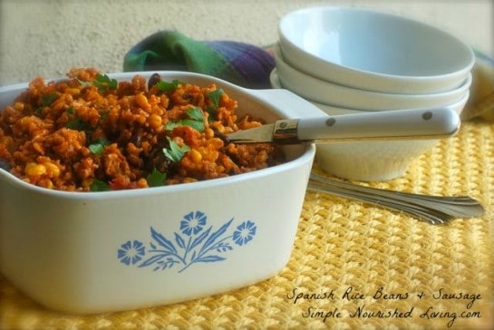 Spanish Rice Beans Sausage in white Corning casserole dish with serving spoon.