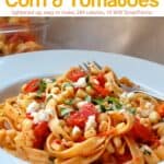 Fettuccine pasta with fresh corn and tomatoes garnished with crumbled cheese and fresh herbs in white bowl with fork.