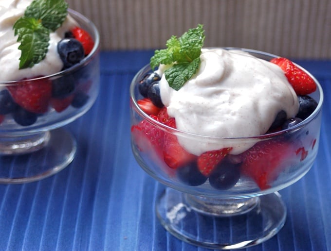 Fresh blueberries and strawberries in a chilled dessert glass topped with cinnamon kissed Greek yogurt and fresh mint.