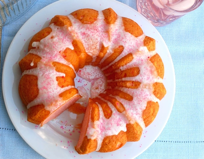 Iced pink lemonade bundt cake with piece missing looking down from overhead.