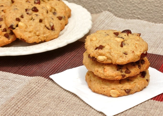 Three Trail Mix Cookies stacked on a napkin next to a plate of cookies