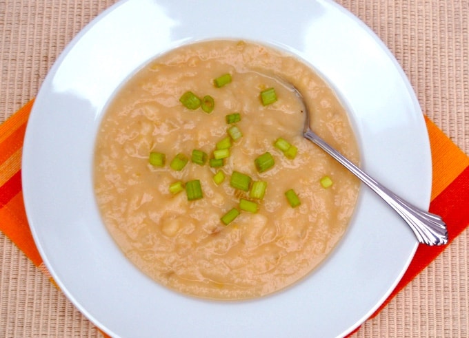 Creamy Cauliflower Potato Soup garnished with sliced green onions in a white bowl