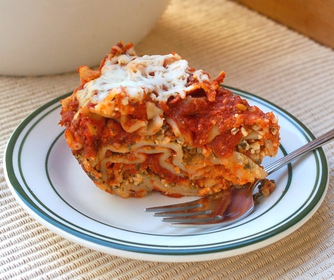 Piece of slow cooker vegetarian lasagna on small white plate with fork.