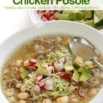 Bowl of chicken posole soup topped with shredded cabbage, chopped radish and avocado.