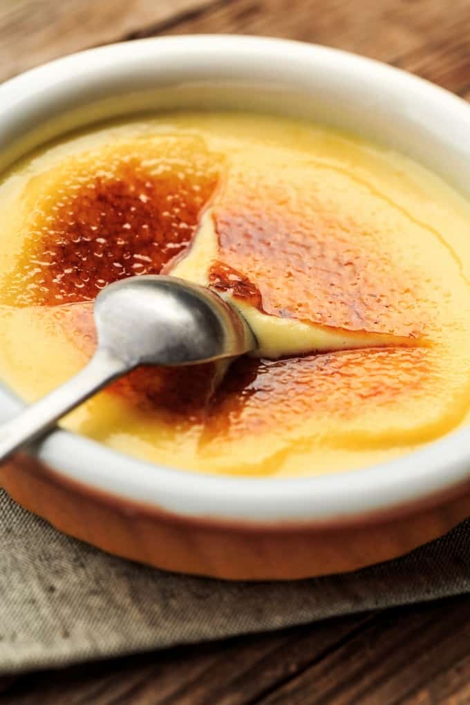 Traditional creamy creme brûlée with crispy sugar topping and dessert spoon. 