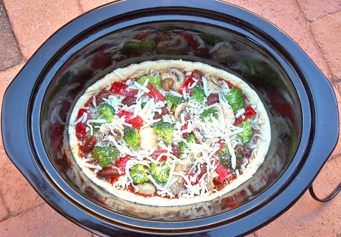 Uncooked vegetable pizza in crock pot.