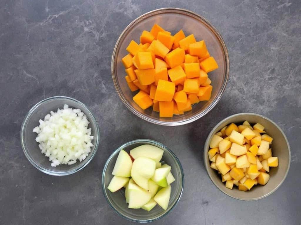 Clear bowls of chopped onion, butternut squash and apple.