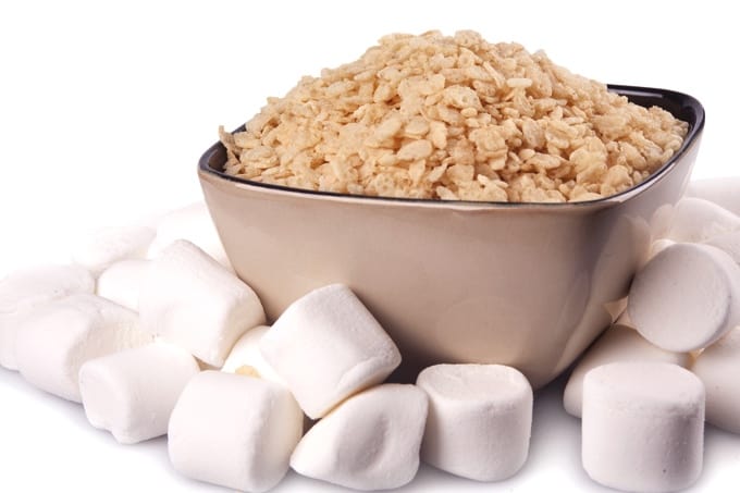 Bowl of Rice Krispies cereal with marshmallows scattered about for making Rice Krispies Treats.