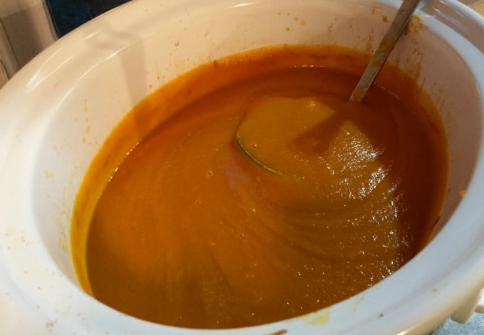 Pureed crock pot curried carrot apple soup with a ladle