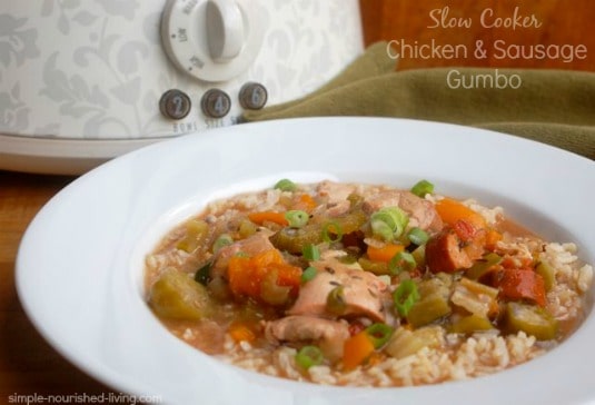 Slow Cooker Chicken and Sausage Gumbo in white bowl with crock pot in the background.