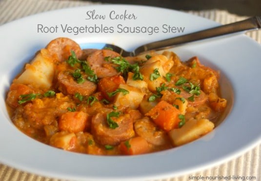 Slow Cooker Root Vegetables and Sausage Stew in white bowl with spoon.