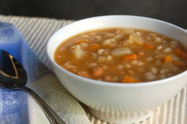 Crock Pot Bean Barley Soup in white bowl with spoon.