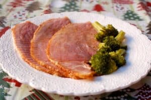 slices of spiral cut ham on a plate with broccoli alongside