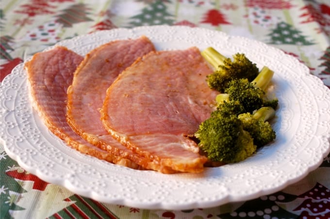 Slices of spiral cut ham on a plate with broccoli alongside.