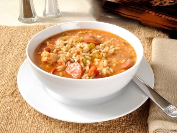 chicken sausage gumbo in white bowl on saucer with spoon