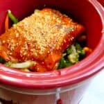 red crock pot with mixed asian vegetables and salmon fillets