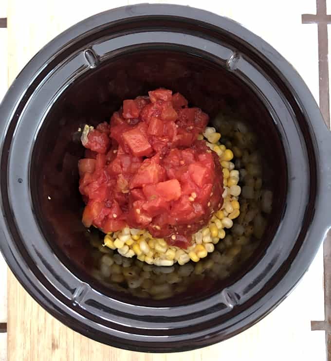 Canned tomatoes with green chilies over corn in crock pot.