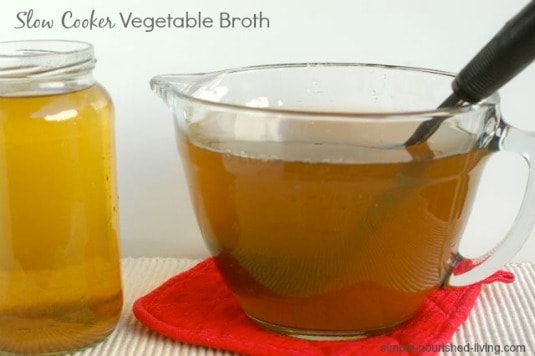 Crock Pot Vegetable Broth in glass measuring cup with ladle.