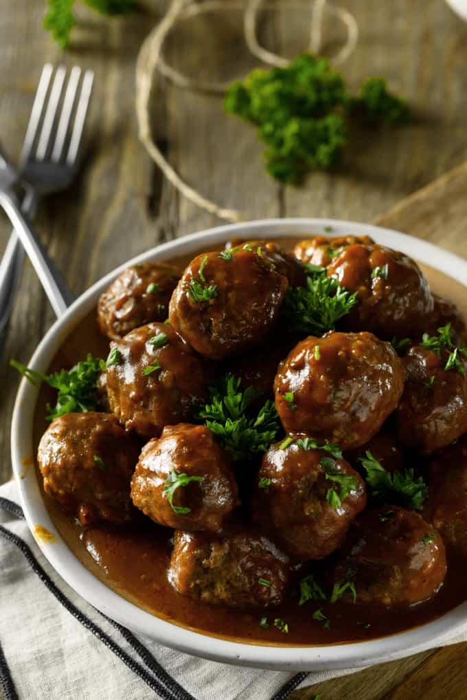 Plate full of French Onion Meatballs garnished with parsley on a wood table