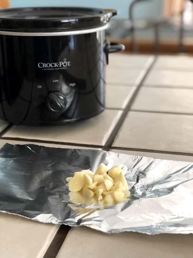 Fresh Cut Garlic Cloves on Tin Foil with Crock Pot in the background
