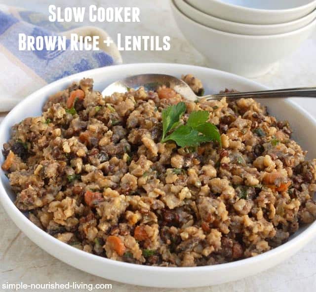 Savory slow cooker brown rice and lentils in serving dish with spoon.