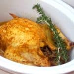 whole chicken with rosemary sprig in white crockpot