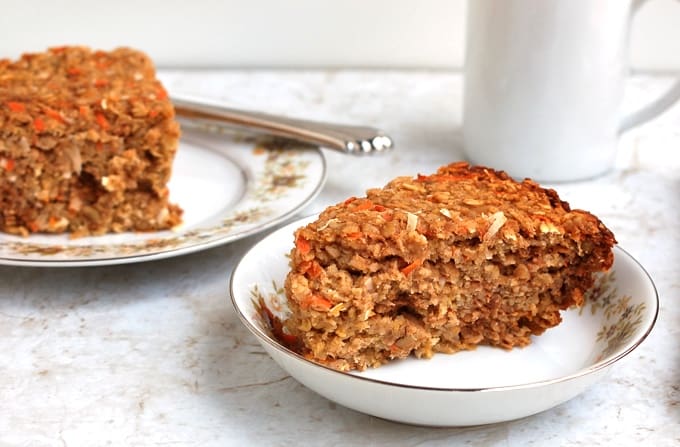Slice of Carrot Cake Baked Oatmeal in a bowl with mug in the background