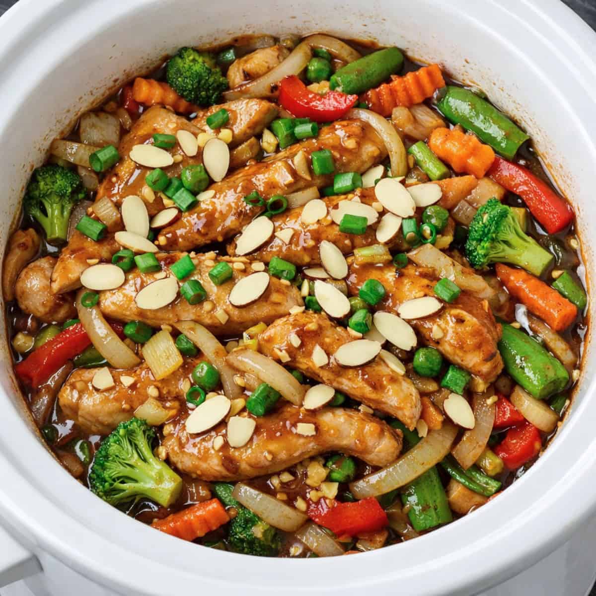 Slow Cooker Ginger-Almond Chicken in a white slow cooker.