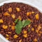 Caribbean Black Beans with Mango topped with fresh cilantro in a white serving dish