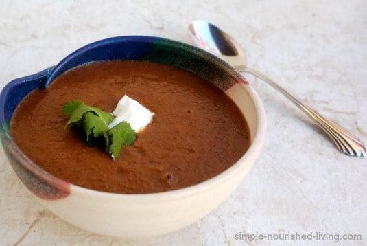 Black bean soup in ceramic bowl with cilantro and dollop of sour cream.