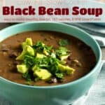 Black bean soup in blue bowl garnished with chopped avocado and cilantro.