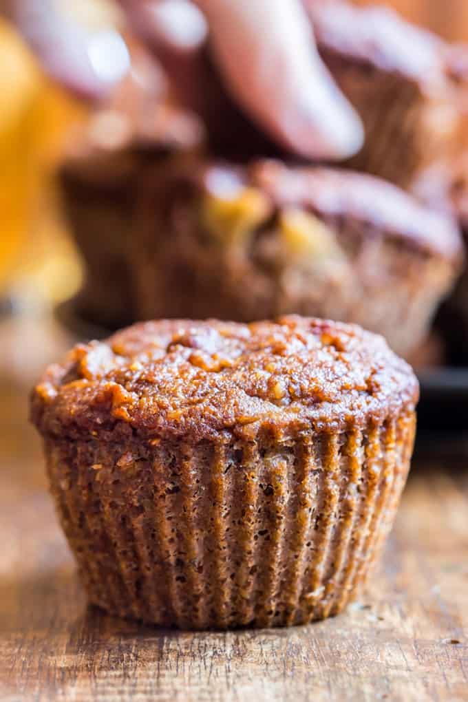 Banana Bran Muffin up close with a hand grabbing another muffin in the background